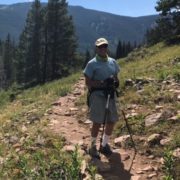 man standing on hiking trail in nature with a camera on a tripod